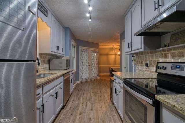 34 Sassafras Grv, Dawsonville, GA 30534 - kitchen featuring stainless steel appliances, under cabinet range hood, a sink, backsplash, and light wood finished floors