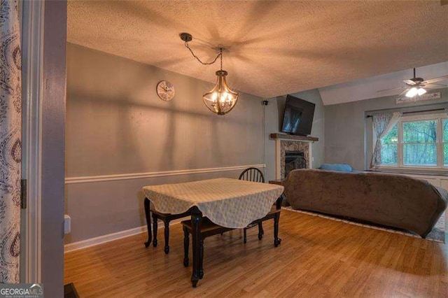 34 Sassafras Grv, Dawsonville, GA 30534 - dining space featuring a textured ceiling, light wood finished floors, baseboards, a fireplace, and a chandelier