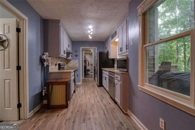 34 Sassafras Grv, Dawsonville, GA 30534 - kitchen featuring appliances with stainless steel finishes, backsplash, a textured ceiling, light wood-style flooring, and baseboards