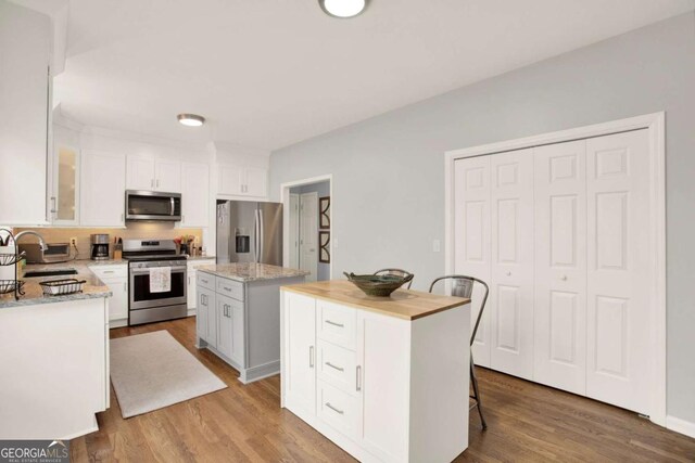 224 Mountain View Dr, Woodstock, GA 30188 - kitchen with appliances with stainless steel finishes, a sink, a kitchen island, white cabinetry, and light wood-style flooring