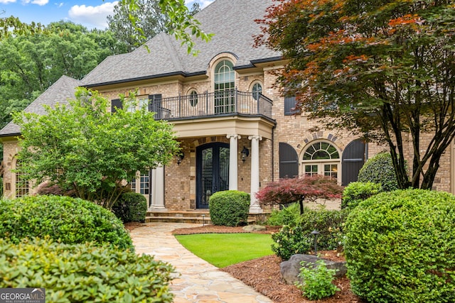 816 Blackfoot Trl, Suwanee, GA 30024 - french country style house with a balcony, brick siding, and roof with shingles