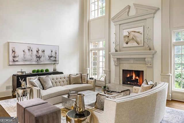 816 Blackfoot Trl, Suwanee, GA 30024 - living area featuring a premium fireplace, a towering ceiling, wood finished floors, and healthy amount of natural light