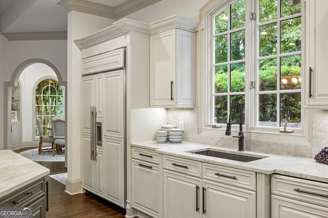 816 Blackfoot Trl, Suwanee, GA 30024 - kitchen with a sink, arched walkways, paneled refrigerator, light stone counters, and dark wood finished floors