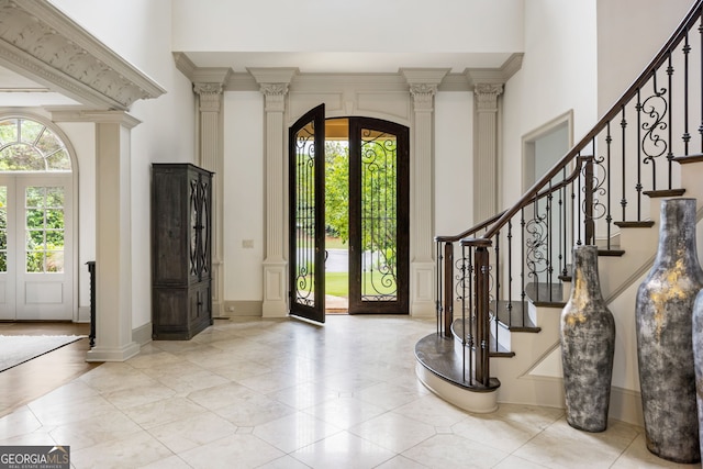 816 Blackfoot Trl, Suwanee, GA 30024 - foyer featuring a high ceiling, french doors, ornate columns, arched walkways, and light tile patterned floors