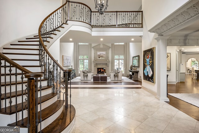 816 Blackfoot Trl, Suwanee, GA 30024 - foyer entrance featuring a high ceiling, stairway, a lit fireplace, decorative columns, and baseboards