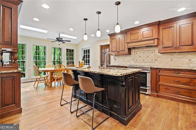 4402 Windsor Oaks Chase, Marietta, GA 30066 - kitchen featuring stainless steel electric stove, light wood finished floors, a skylight, a breakfast bar area, and recessed lighting