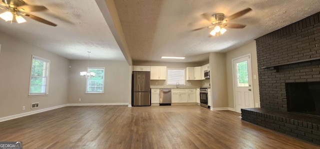 2663 Washington St NW, Atlanta, GA 30318 - unfurnished living room featuring ceiling fan, dark wood-style flooring, a fireplace, a chandelier, and a textured ceiling
