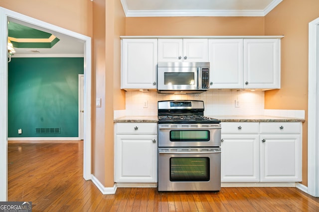 120 Bent Creek Dr, Woodstock, GA 30189 - kitchen with stainless steel appliances, ornamental molding, backsplash, white cabinetry, and light wood-type flooring