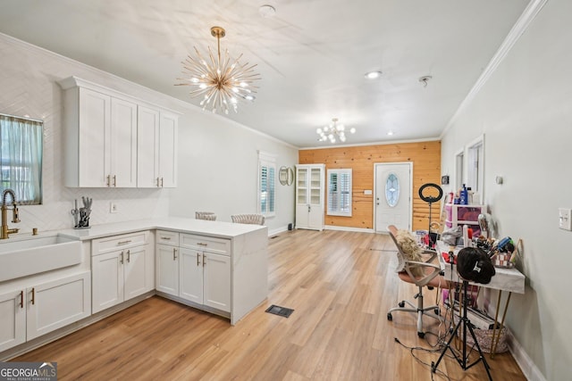 999 Smith St SW, Atlanta, GA 30310 - kitchen with a chandelier, ornamental molding, a peninsula, white cabinetry, and light wood finished floors
