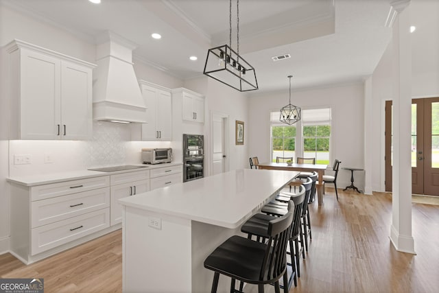 31 Bitter End Ct, Waverly, GA 31565 - kitchen with wall chimney exhaust hood, oven, a kitchen island, ornamental molding, and light wood-type flooring