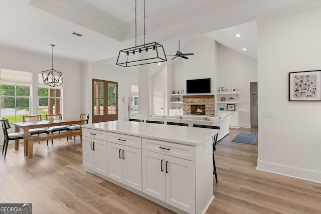 31 Bitter End Ct, Waverly, GA 31565 - kitchen with a fireplace, a ceiling fan, a center island, ornamental molding, and white cabinetry
