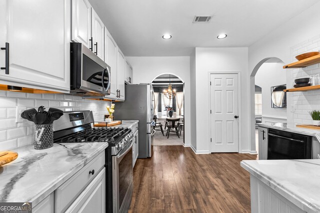 3 Stonebridge Way, Newnan, GA 30265 - kitchen with stainless steel appliances, arched walkways, dark wood-style floors, white cabinets, and tasteful backsplash