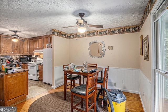 198 Hickory Ave, Demorest, GA 30535 - dining room with ceiling fan, a wainscoted wall, a textured ceiling, and light wood-type flooring