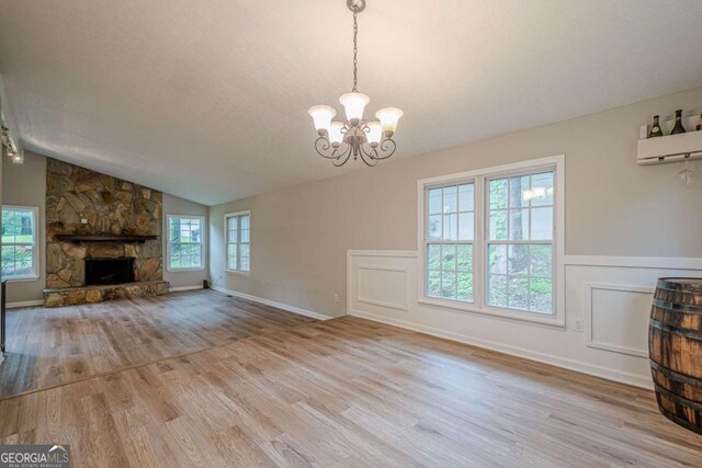 1137 Poplar Log Pl, Austell, GA 30168 - unfurnished living room with wood finished floors, a chandelier, a stone fireplace, vaulted ceiling, and a textured ceiling
