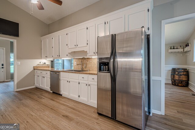1137 Poplar Log Pl, Austell, GA 30168 - kitchen with stainless steel appliances, a sink, white cabinets, light wood finished floors, and vaulted ceiling