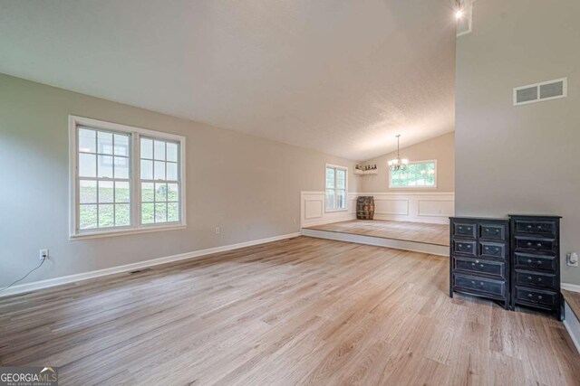 1137 Poplar Log Pl, Austell, GA 30168 - unfurnished living room with a chandelier, light wood-type flooring, vaulted ceiling, and baseboards