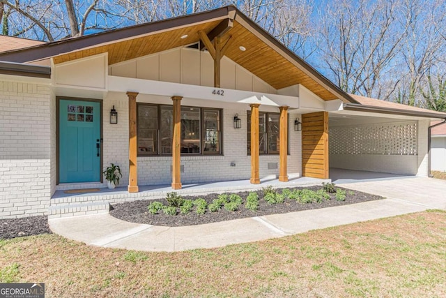 442 Mountain Park Trl, Stone Mountain, GA 30087 - view of front facade with brick siding, covered porch, board and batten siding, concrete driveway, and a carport
