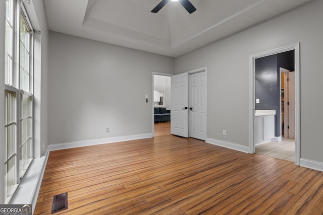 1133 Stone Brook Ln, Bremen, GA 30110 - unfurnished bedroom with a raised ceiling, light wood finished floors, connected bathroom, baseboards, and ceiling fan