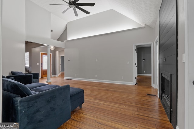 1133 Stone Brook Ln, Bremen, GA 30110 - living area featuring ceiling fan, lofted ceiling, a large fireplace, hardwood / wood-style flooring, and decorative columns