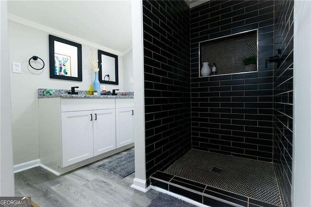 2190 Gordon Cir SE, Smyrna, GA 30080 - bathroom featuring crown molding, wood finished floors, double vanity, a tile shower, and baseboards