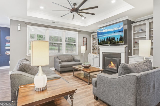 160 Amherst Way, Fayetteville, GA 30215 - living area with a raised ceiling, ornamental molding, light wood-style flooring, a ceiling fan, and a warm lit fireplace