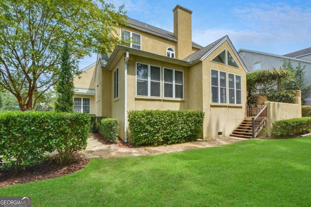 180 Shadow Wood Bnd, Saint Simons, GA 31522 - rear view of property featuring stucco siding, a lawn, and a chimney