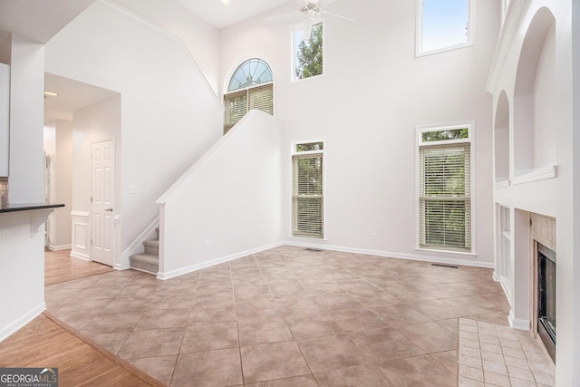 2330 Springmonte Pl, Cumming, GA 30041 - unfurnished living room with stairs, ceiling fan, light tile patterned floors, a towering ceiling, and a fireplace