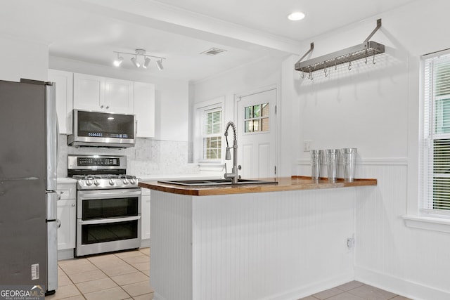 1844 Stanton St, Decatur, GA 30032 - kitchen with stainless steel appliances, a sink, light tile patterned floors, white cabinets, and plenty of natural light