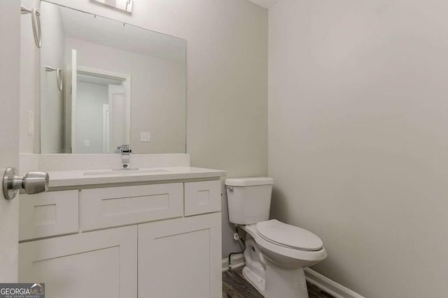 5352 Windfern Ct, Stone Mountain, GA 30088 - half bath with toilet, baseboards, vanity, and wood finished floors