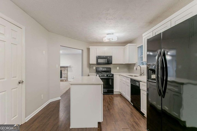 5352 Windfern Ct, Stone Mountain, GA 30088 - kitchen with black appliances, a center island, a sink, light countertops, and white cabinets