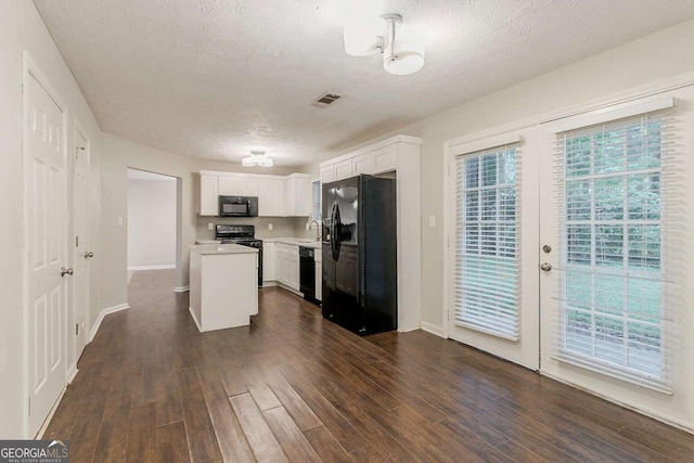 5352 Windfern Ct, Stone Mountain, GA 30088 - kitchen with black appliances, a textured ceiling, light countertops, dark wood-type flooring, and white cabinetry