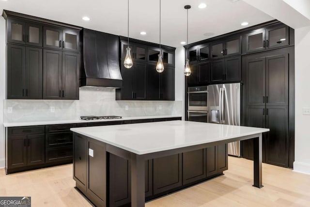 1050 Carnoustie, Greensboro, GA 30642 - kitchen with stainless steel appliances, custom exhaust hood, a kitchen island, backsplash, and light wood-type flooring