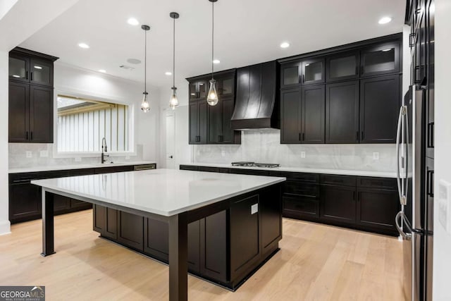 1050 Carnoustie, Greensboro, GA 30642 - kitchen with gas stovetop, premium range hood, tasteful backsplash, a kitchen island, and light wood-type flooring