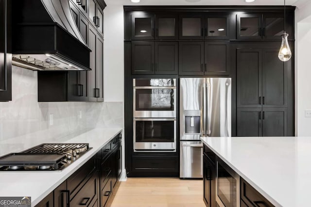 1050 Carnoustie, Greensboro, GA 30642 - kitchen featuring appliances with stainless steel finishes, custom range hood, light countertops, light wood finished floors, and glass insert cabinets