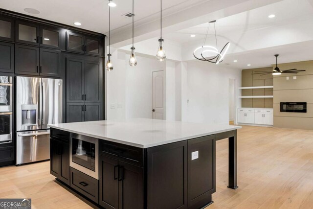 1050 Carnoustie, Greensboro, GA 30642 - kitchen featuring stainless steel refrigerator with ice dispenser, built in microwave, light wood-style floors, light countertops, and decorative light fixtures
