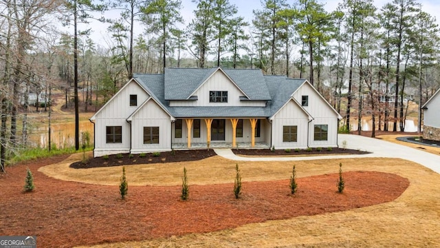 1050 Carnoustie, Greensboro, GA 30642 - modern inspired farmhouse featuring a porch, a shingled roof, board and batten siding, and view of scattered trees