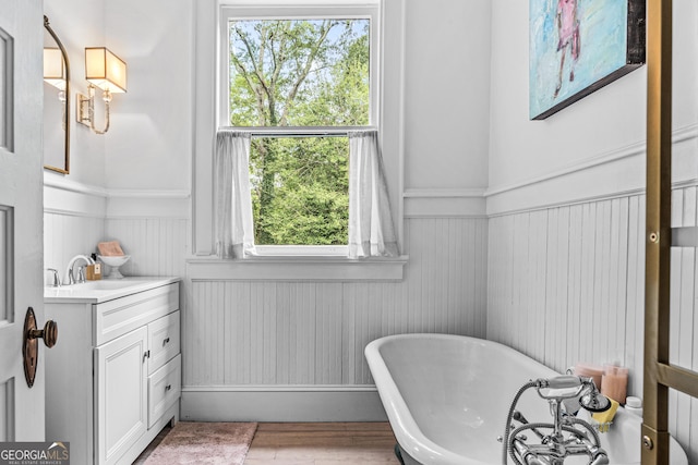 766 E Ave, Madison, GA 30650 - bathroom featuring a wainscoted wall, a freestanding bath, vanity, and wood finished floors