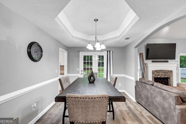 3190 Water Brook Dr SW, Conyers, GA 30094 - dining area with a textured ceiling, wood finished floors, a stone fireplace, a chandelier, and a raised ceiling