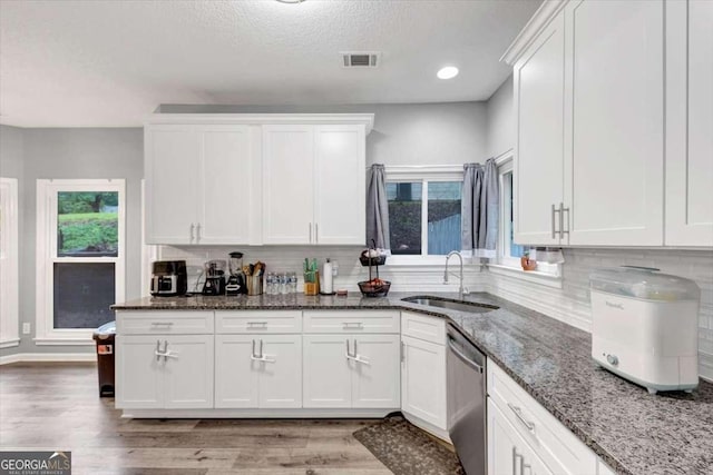 3190 Water Brook Dr SW, Conyers, GA 30094 - kitchen with stainless steel dishwasher, a sink, white cabinets, tasteful backsplash, and light wood-style floors