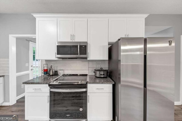 3190 Water Brook Dr SW, Conyers, GA 30094 - kitchen featuring appliances with stainless steel finishes, white cabinets, dark stone countertops, and dark wood-style flooring