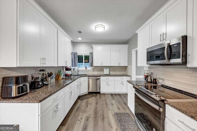 3190 Water Brook Dr SW, Conyers, GA 30094 - kitchen with stainless steel appliances, a sink, tasteful backsplash, white cabinets, and a textured ceiling