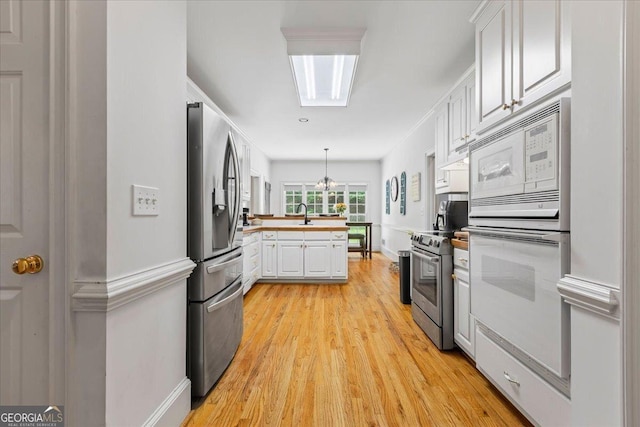 40 Costleys Bridge Dr, Oxford, GA 30054 - kitchen featuring appliances with stainless steel finishes, white cabinetry, a chandelier, a peninsula, and light wood-style flooring