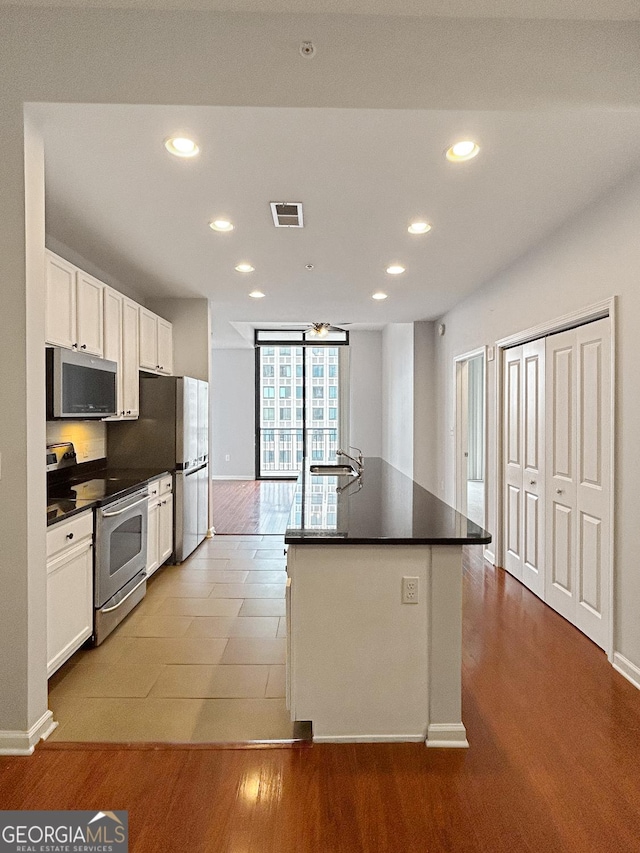 3040 Peachtree Rd Unit 1501, Atlanta, GA 30305 - kitchen with appliances with stainless steel finishes, recessed lighting, dark countertops, white cabinets, and a kitchen island with sink