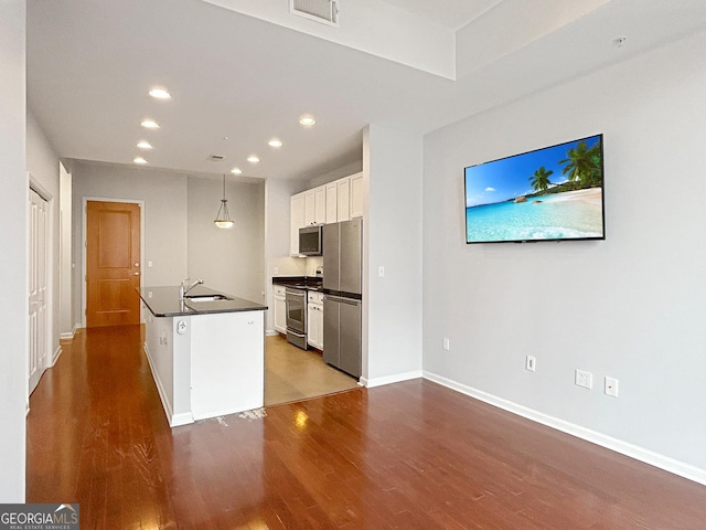 3040 Peachtree Rd Unit 1501, Atlanta, GA 30305 - kitchen with appliances with stainless steel finishes, dark countertops, dark wood-style floors, white cabinets, and a sink