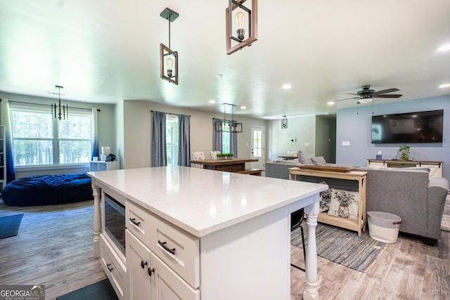 101 Crestwood Dr, Lagrange, GA 30241 - kitchen with stainless steel microwave, open floor plan, a kitchen island, light wood-style flooring, and white cabinetry