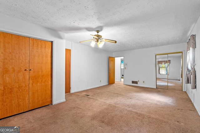 900 Fleetwood Cir SW, Atlanta, GA 30311 - unfurnished bedroom featuring multiple closets, carpet floors, baseboards, a textured ceiling, and ceiling fan