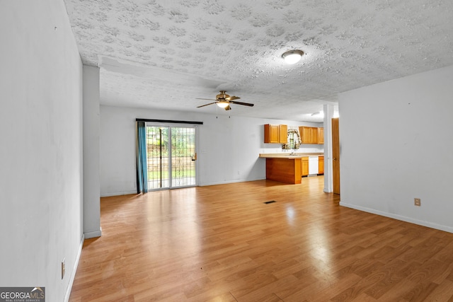 900 Fleetwood Cir SW, Atlanta, GA 30311 - unfurnished living room featuring light wood-style flooring, ceiling fan, baseboards, and a textured ceiling