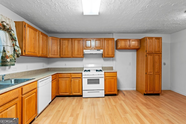 900 Fleetwood Cir SW, Atlanta, GA 30311 - kitchen featuring white appliances, under cabinet range hood, brown cabinetry, light wood-type flooring, and a textured ceiling