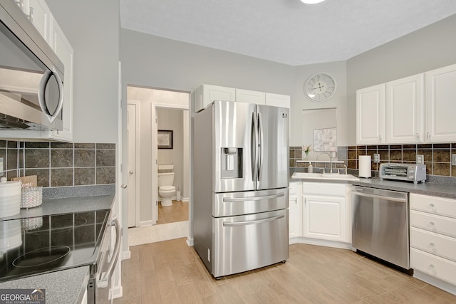 17 Roxbury Ln, Newnan, GA 30265 - kitchen featuring stainless steel appliances, a sink, white cabinetry, light wood-type flooring, and backsplash