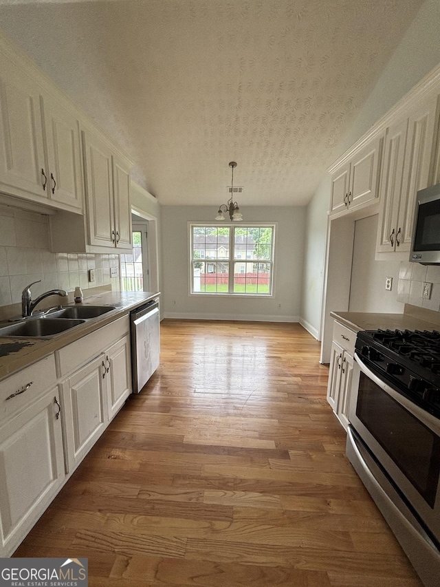 4069 Savannah Ridge Ct, Loganville, GA 30052 - kitchen with stainless steel appliances, a sink, a textured ceiling, white cabinets, and decorative backsplash